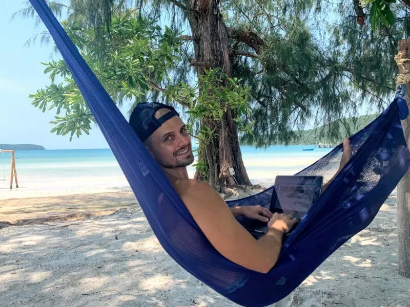 man swinging in hammock working on his laptop searching for entry-level digital nomad jobs