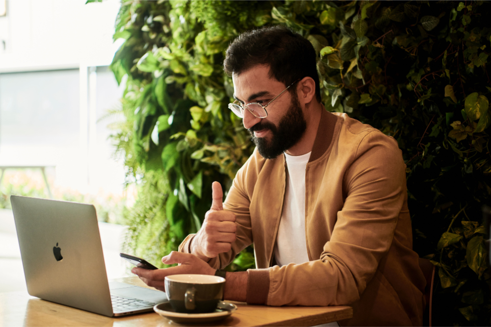 man showing a thumbs up in front of laptop