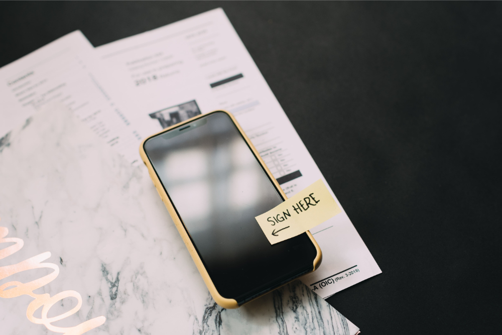 smartphone with contracts and note that says sign here